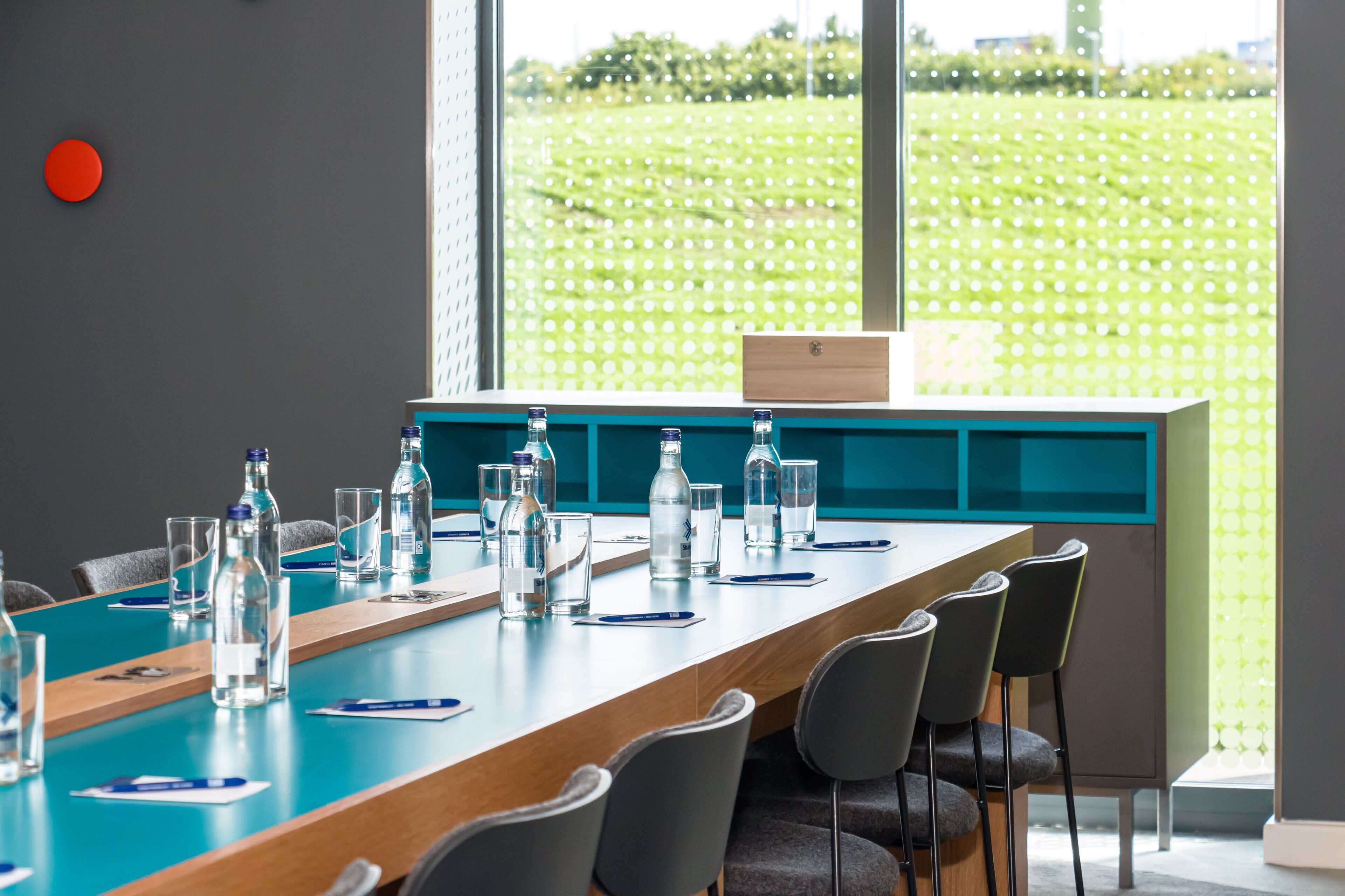 A conference room with a long table, chairs, and water bottles.