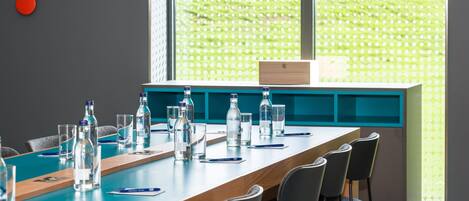 Une salle de conférence avec une longue table, des chaises et des bouteilles d’eau.