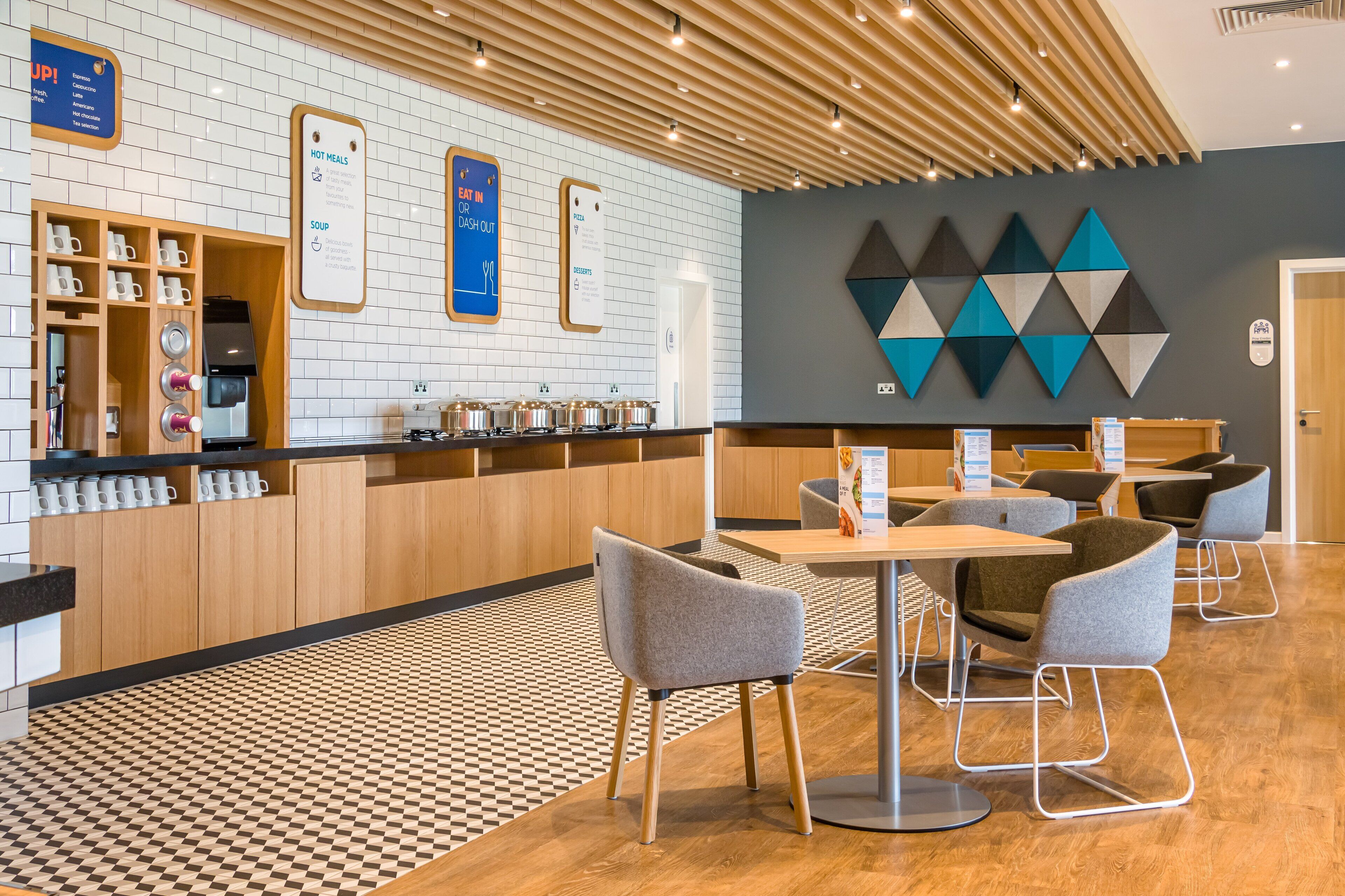 A modern cafe with a checkered floor, wooden counter, and seating area.