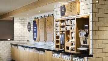 A modern coffee bar with a menu board, espresso machine, and neatly organized condiment dispensers.