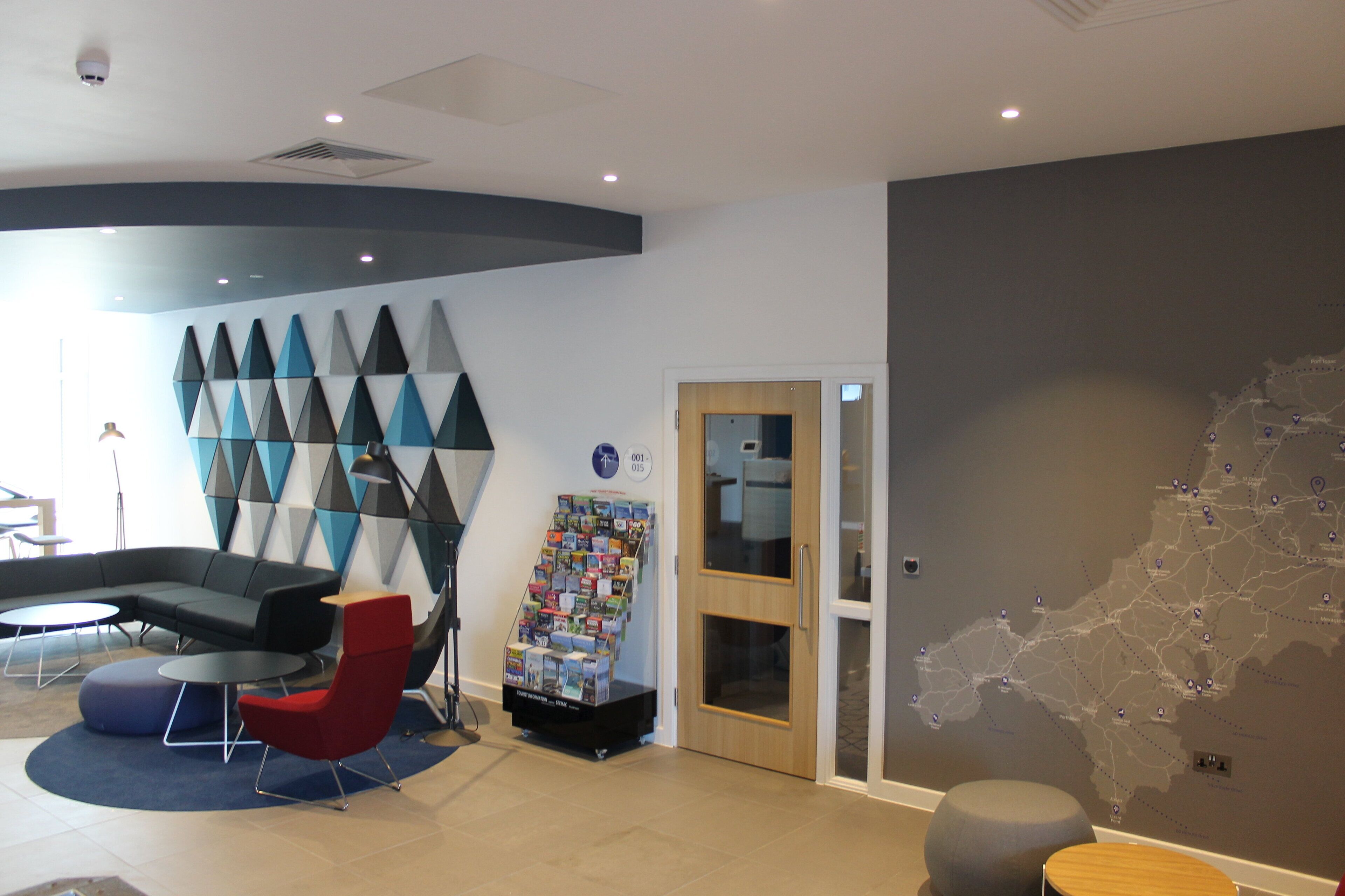 A modern lobby with a curved seating area, a map on the wall, and a door leading to another room.
