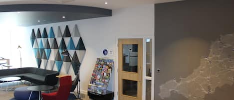 A modern lobby with a curved seating area, a map on the wall, and a door leading to another room.