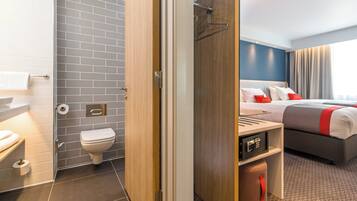 A hotel room with a bathroom, a bed, and a desk.