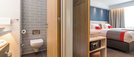 A hotel room with a bathroom, a bed, and a desk.