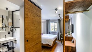 A modern bedroom with a wooden door, a large window, and a bedside table. - BIO-Hotel Adler (Vogt)