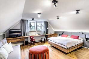 Un dormitorio moderno con cama tipo loft, un escritorio, un televisor y una zona de estar cómoda.