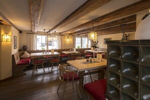 Un restaurante acogedor con vigas de madera, asientos acolchados en rojo e iluminación colgante.