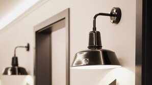 A hallway with white walls, numbered doors, and wall-mounted lamps. - BIO-Hotel Adler (Vogt)
