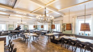 A spacious dining area with multiple seating options, including tables and booths, and a grand piano in the corner. - BIO-Hotel Adler (Vogt)