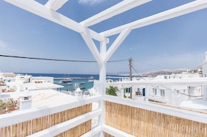 A balcony with a view of a harbor, white buildings, and a clear blue sky.