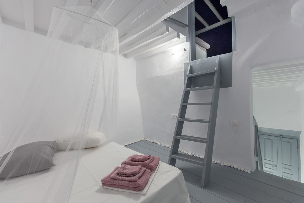 Een slaapkamer met een bed, een ladder en een balkon.