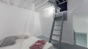 A bedroom with a bed, a ladder, and a balcony.