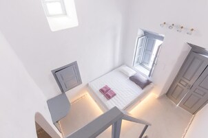 A bedroom with a bed, a desk, and a window.