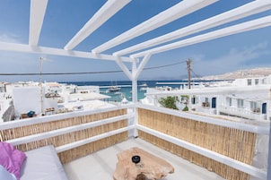 A balcony with a view of the sea and white buildings.