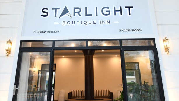 L'esterno del Starlight Boutique Inn con un doppio ingresso, un'area reception con divano e piante in vaso, e una vista chiara sull'interno tramite le porte in vetro.