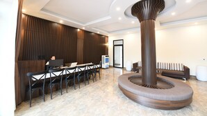 Una hall moderna con reception, area lounge e una colonna centrale originale.