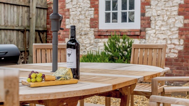 Una mesa de madera con una botella de vino, queso y uvas.