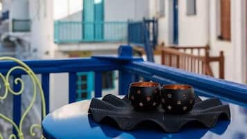 Ein Balkon mit zwei schwarzen Tassen auf einem schwarzen Tablett, mit Blick auf eine Reihe weißer Gebäude mit blauen Balkonen.