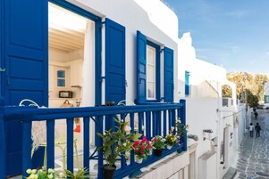 Una calle estrecha con edificios blancos y puertas y contraventanas azules.