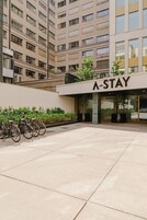 A modern building with a sign reading 'A-STAY' and a bike parking area in front.