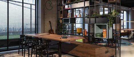 Un espacio de oficina moderno con un escritorio de madera, sillas negras y una estantería llena de libros y objetos decorativos.