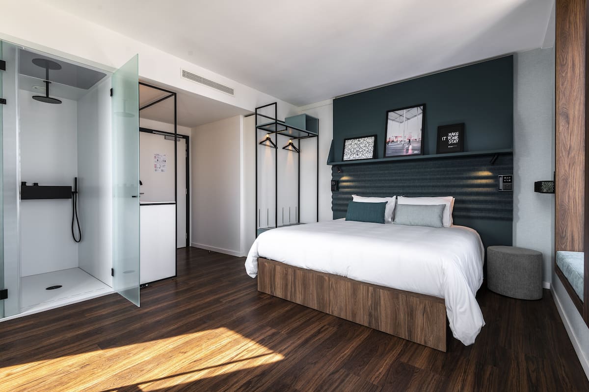 Une chambre moderne avec un grand lit, un dressing et une douche à l’italienne.