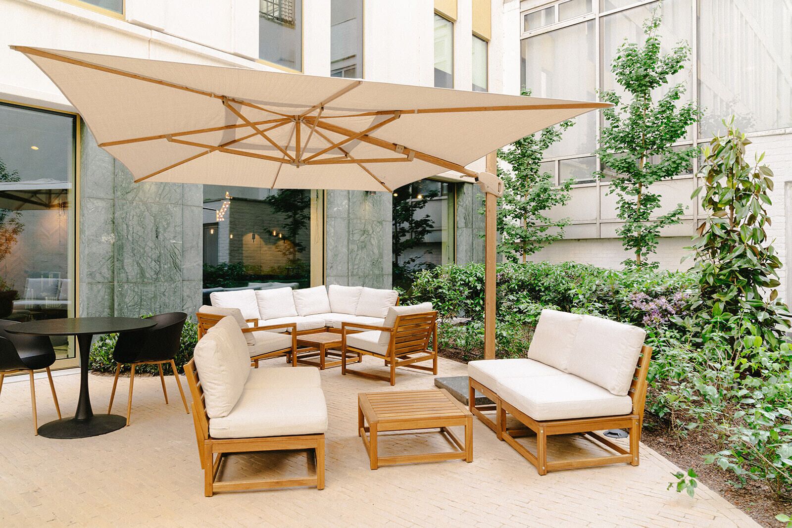 A patio with outdoor furniture, a large umbrella, and a view of a building with large windows.