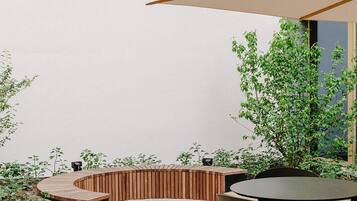 A patio with a round table and chairs, a wooden bench, and a large umbrella.