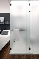 A modern bedroom with a bed, a nightstand, and a wall-mounted towel rack.