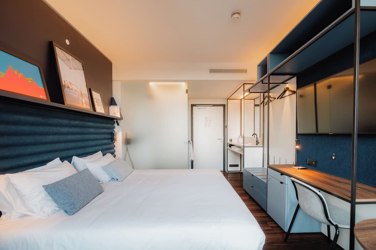 Une chambre d’hôtel moderne, dotée d’un grand lit, d’un bureau et d’une armoire.