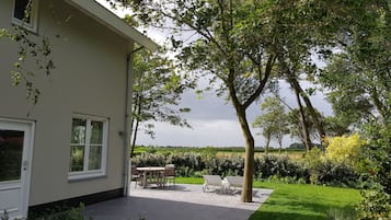 A house with a patio area, a lawn, and a view of the countryside.