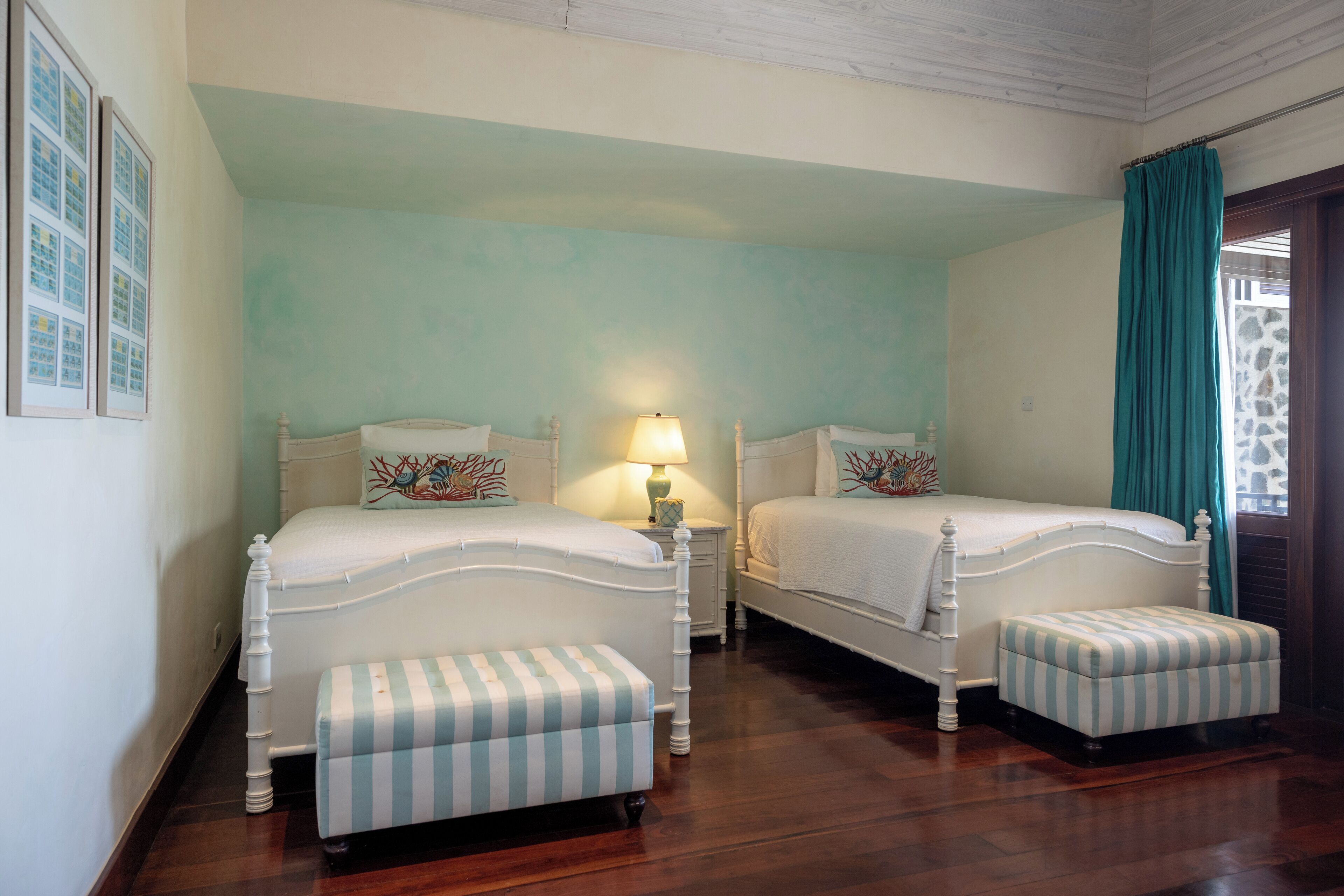 Une chambre avec deux lits, une table de chevet avec une lampe et une fenêtre avec un rideau.