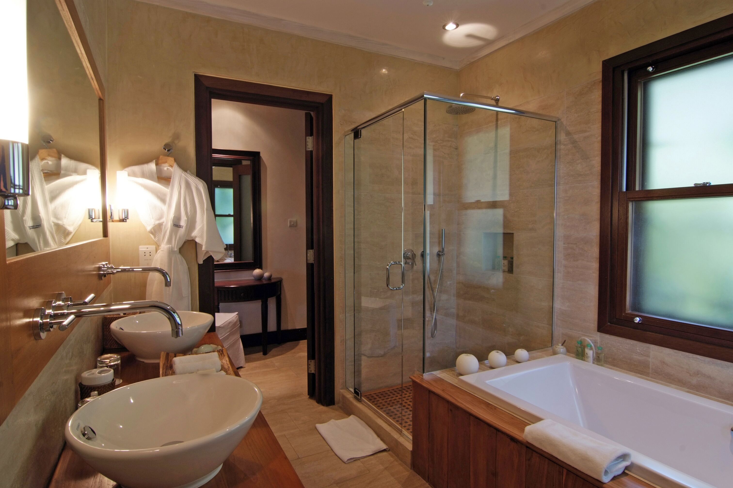 A modern bathroom with a large bathtub, a glass-enclosed shower, a sink, and a mirror.