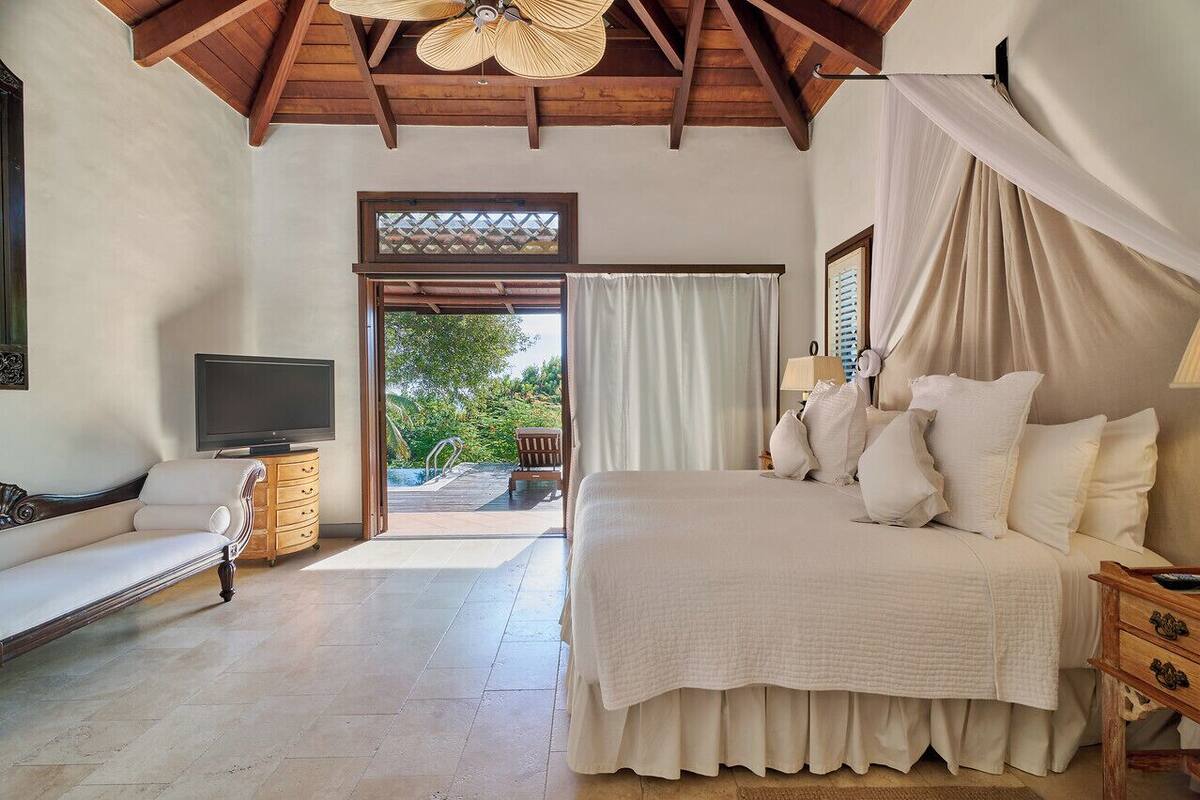 A bedroom with a bed, a TV, a sofa, and a view of the outdoors.