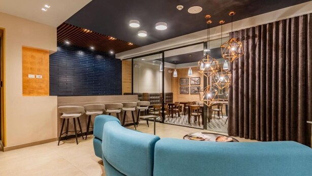 A modern interior with a blue sofa, a dining area, and a kitchen with a black brick wall. - Apartamentos Facile (Bogotá)