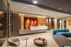 Un área de recepción moderna con mostrador, zona de estar y separador de vidrio.