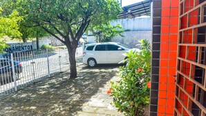 A paved pathway with a tree and a parked white car. - Apartamento Mobiliado Mozart, 105 (Natal)