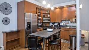 Una cocina moderna con armarios de madera, electrodomésticos de acero inoxidable y una isla central con taburetes.