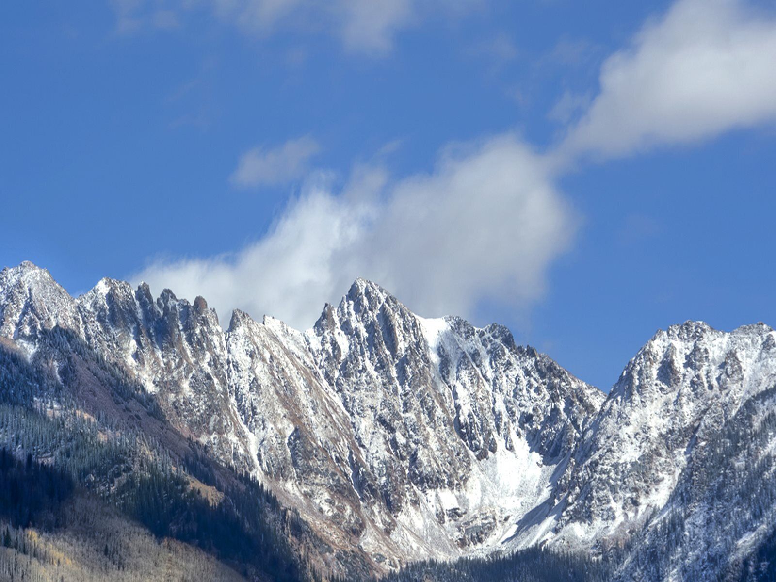 A mountain range with snow-covered peaks and a clear blue sky.