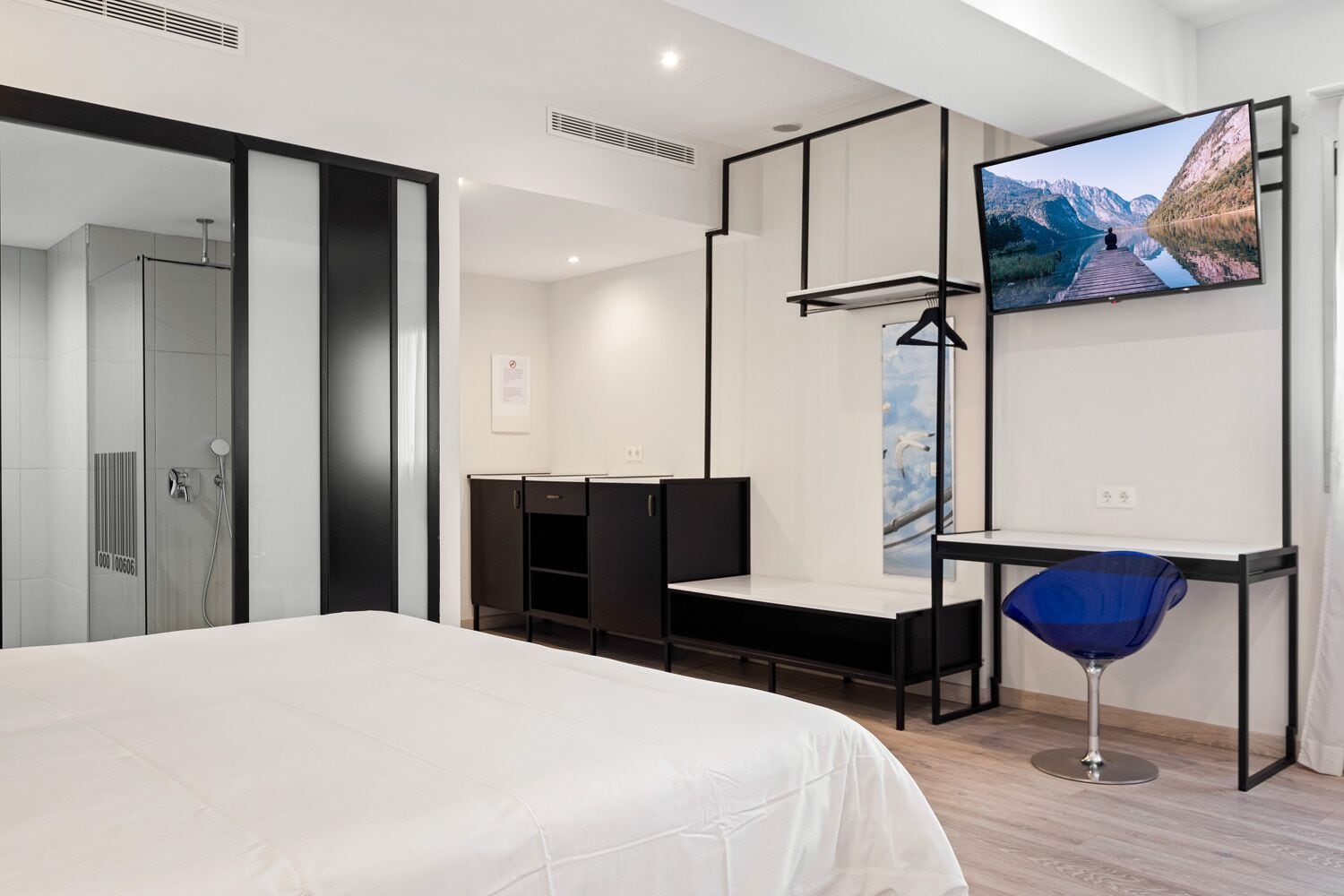 Une chambre d’hôtel moderne avec un grand lit, un téléviseur fixé au mur, un bureau et une chaise.
