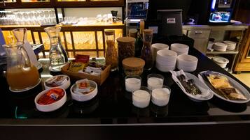 Una barra de desayuno con diferentes alimentos, salsas y una máquina de café.