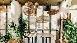 Una habitación con muebles de mimbre, ventanas amplias y lámparas colgantes.