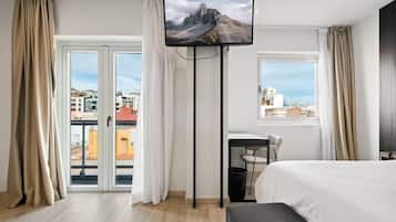 Una habitación de hotel con una cama, un escritorio y un televisor sobre un pedestal.