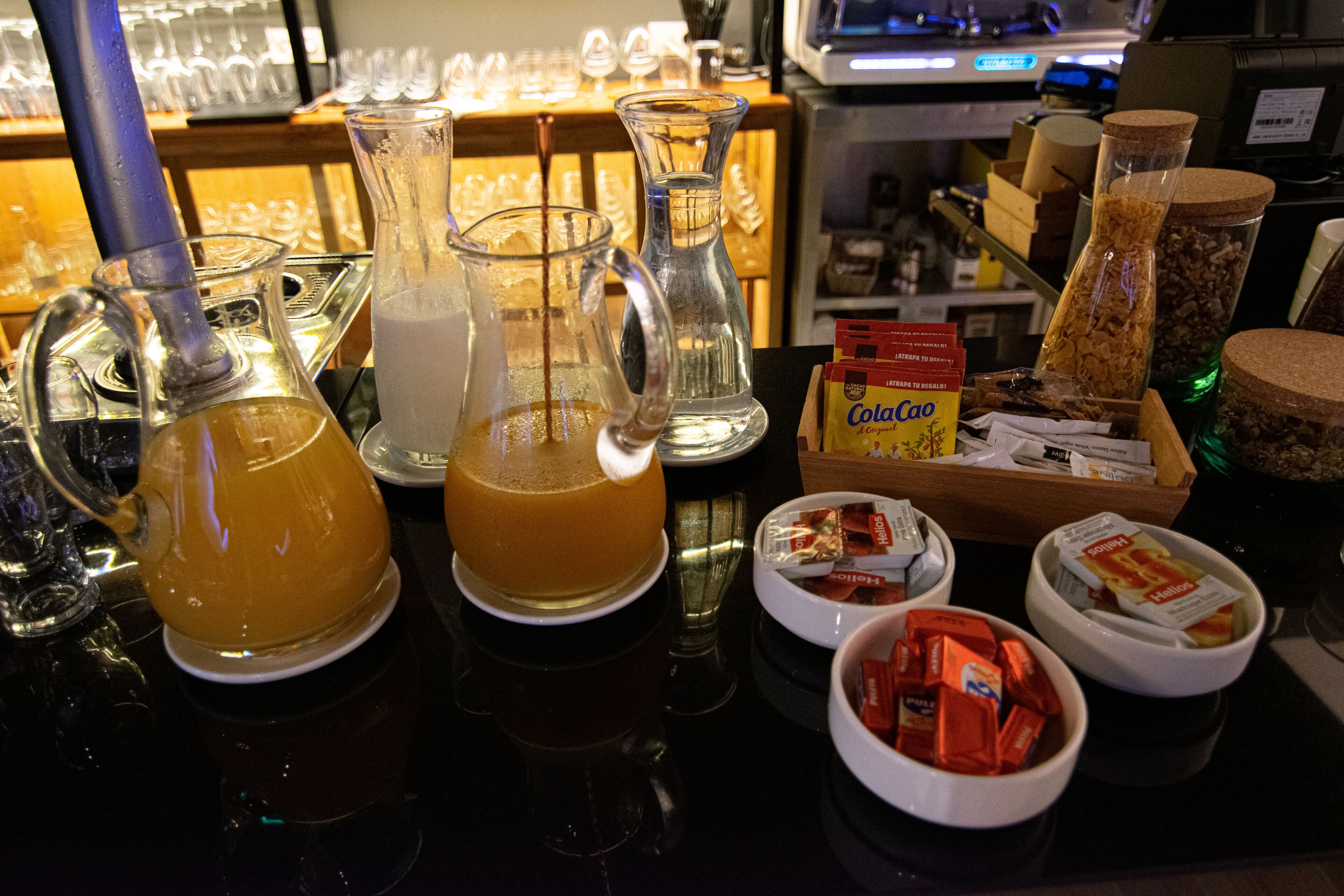 A bar area with various glassware, including a pitcher and a carafe, and a selection of snacks and condiments.