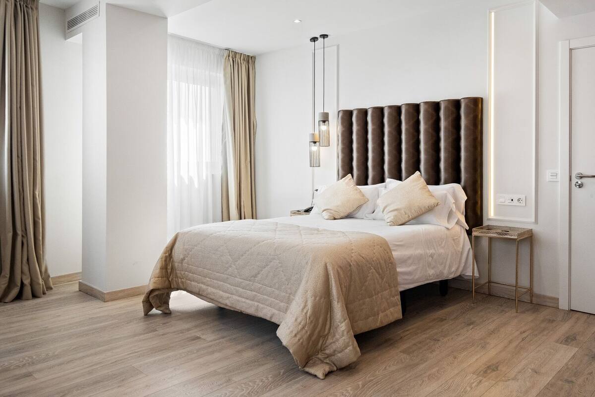 Un dormitorio moderno con una cama grande, una mesita de noche y un pequeño escritorio.