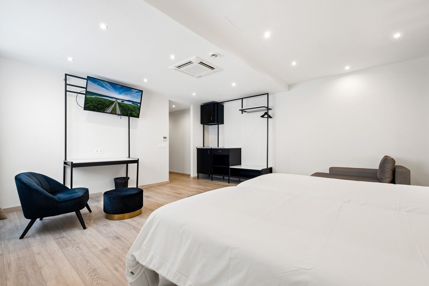 Ein modernes Hotelzimmer mit einem großen Bett, einem Schreibtisch, einem Stuhl, einem Fernseher und einer Couch.