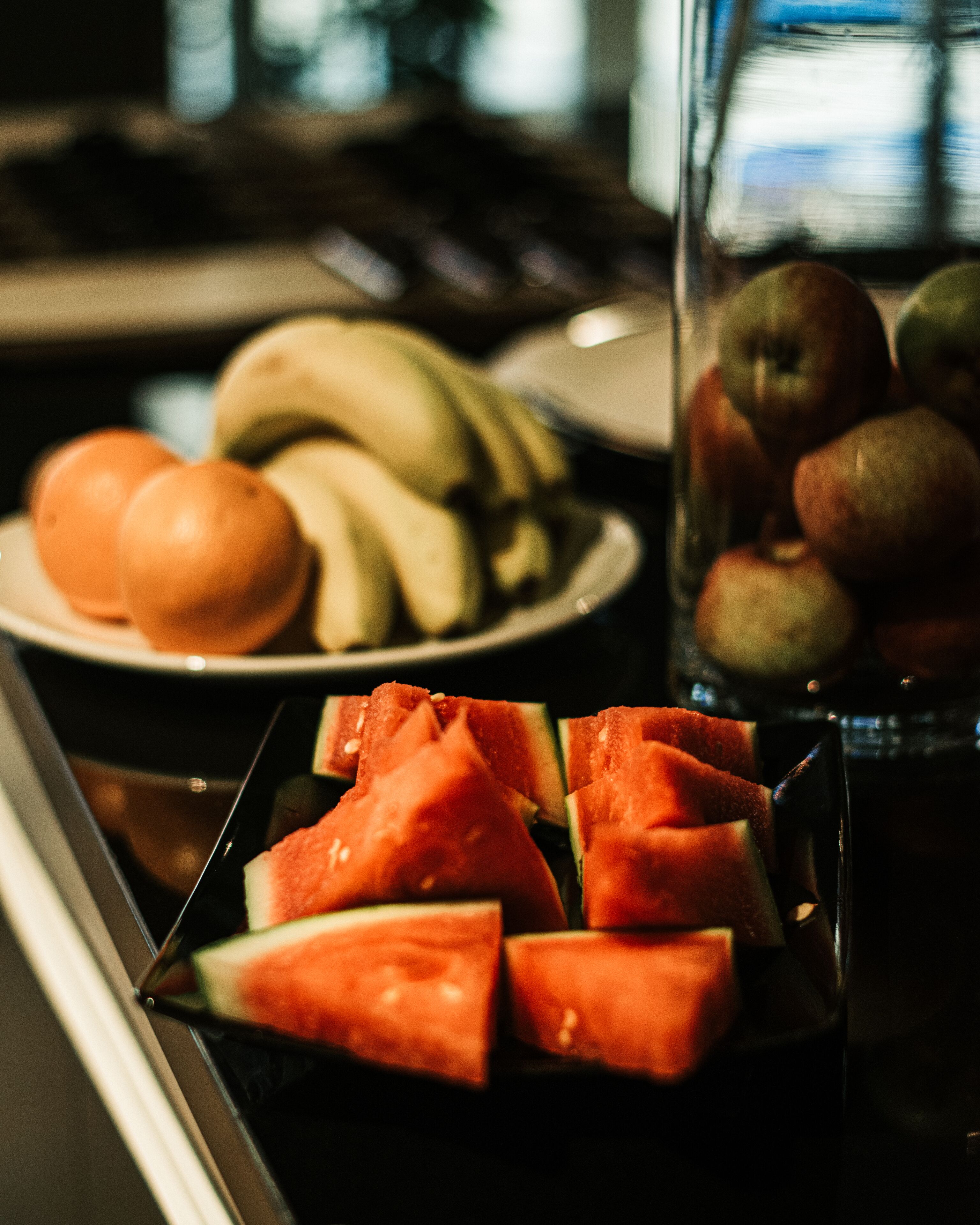 Un cuenco de frutas con plátanos, manzanas y naranjas.