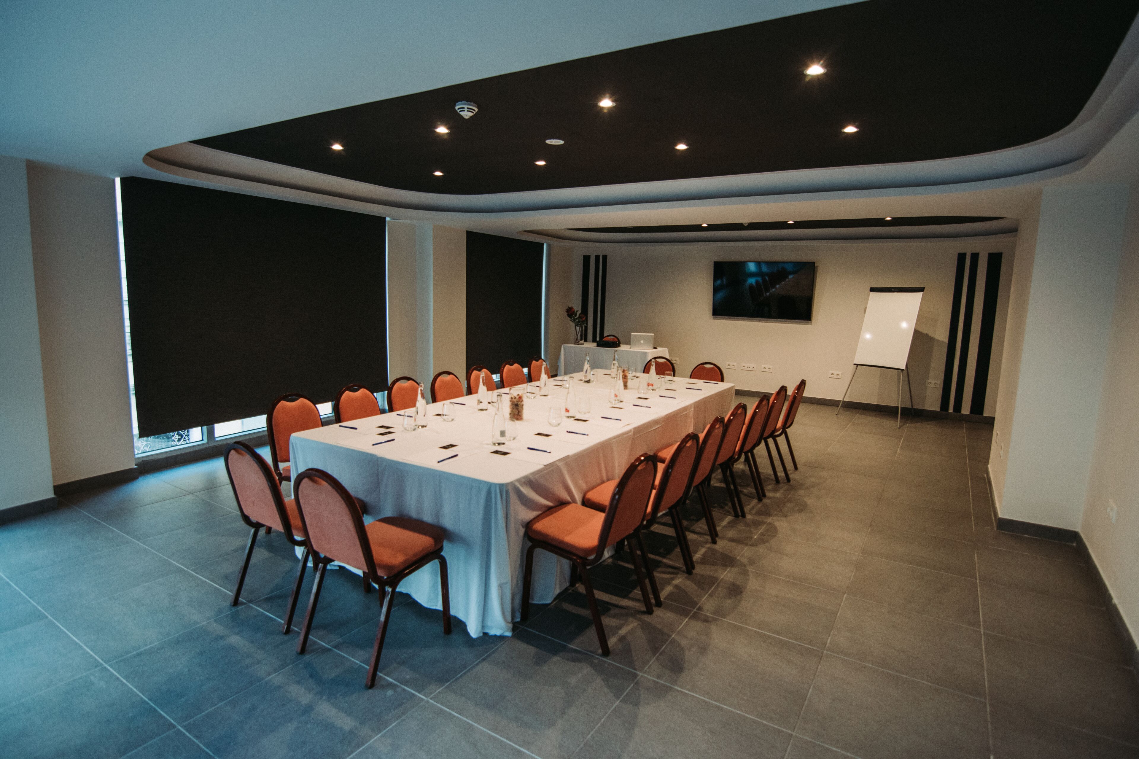 A conference room with a long table, chairs, a projector screen, and a whiteboard.