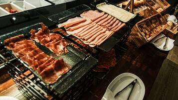 Un bufé con diferentes carnes y pasteles.