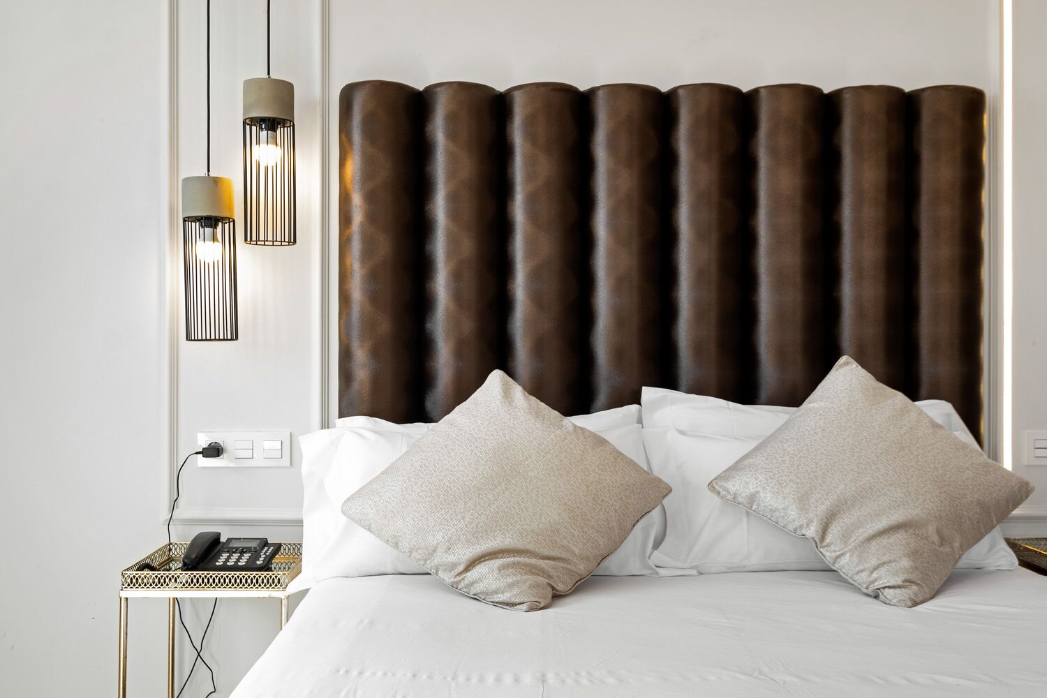 Habitación de hotel con una cama grande, dos lámparas de noche, un teléfono y un enchufe.